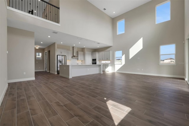 unfurnished living room featuring a wealth of natural light and dark hardwood / wood-style floors