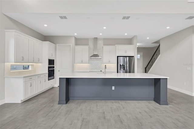 kitchen with oven, white cabinetry, stainless steel fridge with ice dispenser, and wall chimney range hood