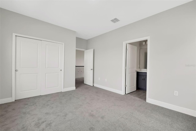 unfurnished bedroom featuring connected bathroom, a closet, and light colored carpet