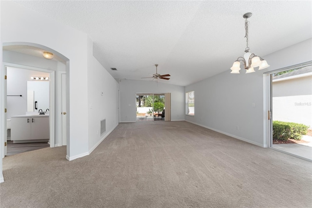 unfurnished living room featuring carpet, ceiling fan with notable chandelier, lofted ceiling, and a textured ceiling