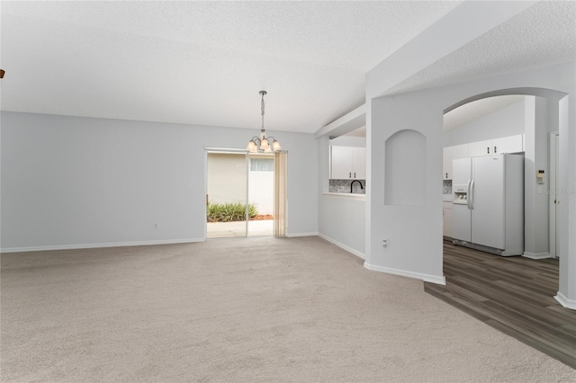 spare room featuring a textured ceiling, lofted ceiling, and an inviting chandelier