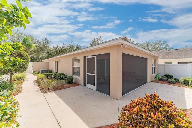 view of property exterior with a sunroom, a patio area, and central air condition unit