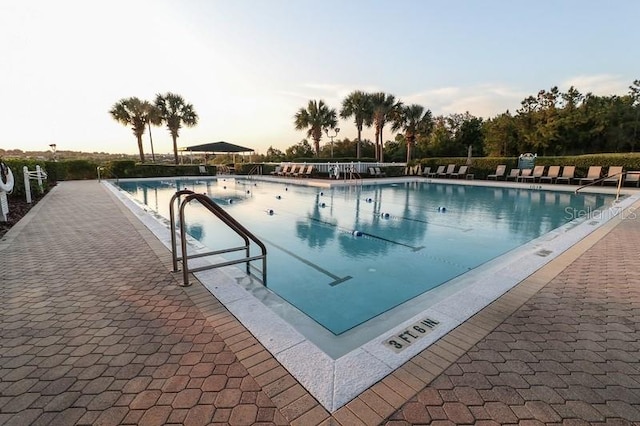 pool at dusk with a patio area