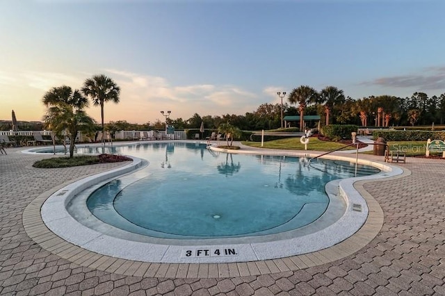 pool at dusk featuring a patio area