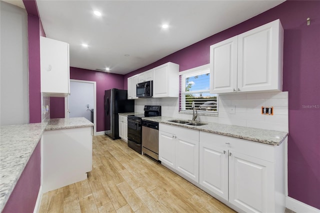 kitchen featuring sink, light hardwood / wood-style flooring, backsplash, white cabinets, and appliances with stainless steel finishes