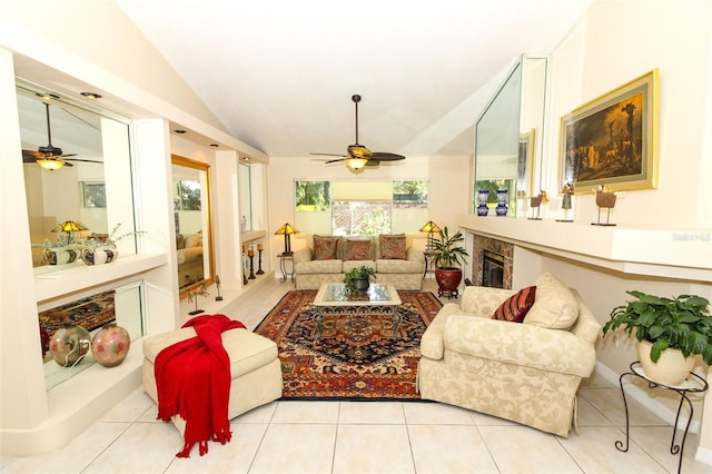 living room featuring ceiling fan, a fireplace, light tile patterned floors, and vaulted ceiling