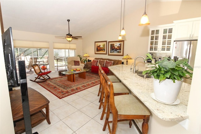 dining space with ceiling fan, sink, light tile patterned floors, and vaulted ceiling