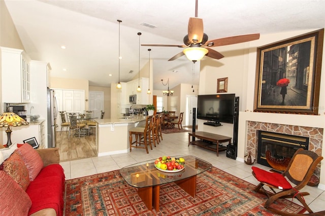 living room featuring light tile patterned floors, a stone fireplace, ceiling fan, and lofted ceiling