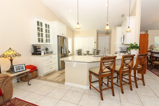 kitchen featuring backsplash, a breakfast bar area, decorative light fixtures, light stone counters, and stainless steel appliances