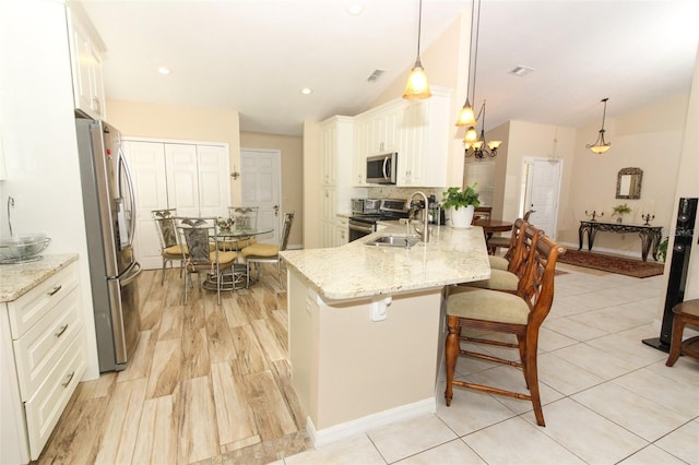 kitchen featuring decorative light fixtures, light stone counters, and appliances with stainless steel finishes