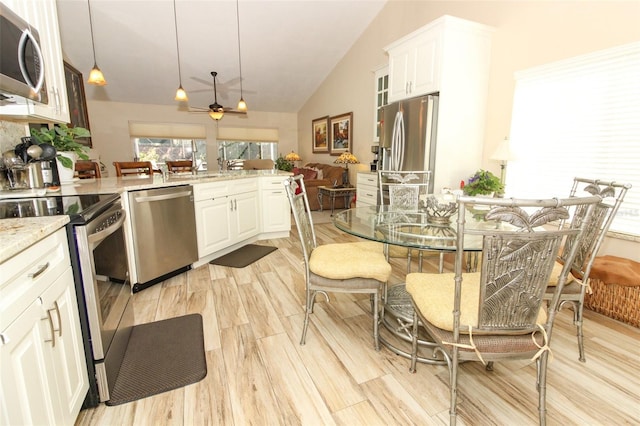 kitchen featuring white cabinetry, light stone countertops, decorative light fixtures, and appliances with stainless steel finishes