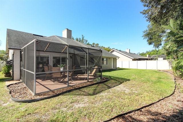 back of property featuring a patio, glass enclosure, and a lawn