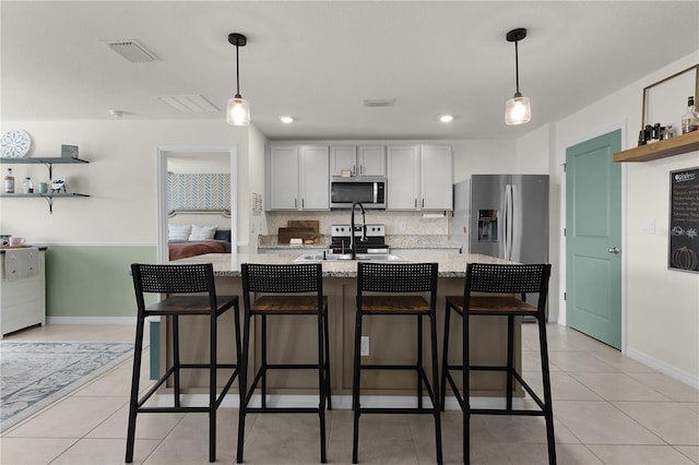 kitchen featuring pendant lighting, a breakfast bar, stainless steel appliances, and a kitchen island with sink