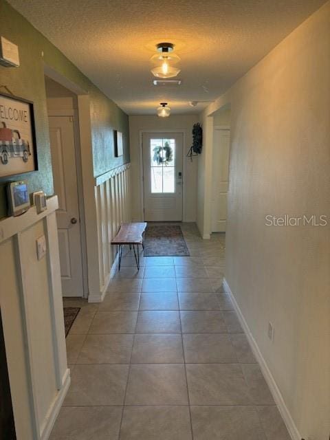 entryway with light tile patterned floors and a textured ceiling