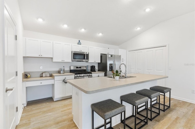 kitchen with a center island with sink, sink, white cabinets, appliances with stainless steel finishes, and light hardwood / wood-style floors