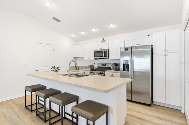 kitchen with lofted ceiling, white cabinets, a center island with sink, sink, and stainless steel appliances