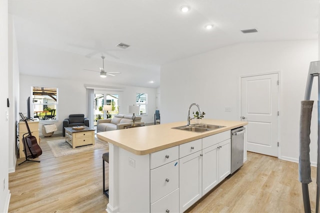 kitchen featuring dishwasher, an island with sink, sink, light wood-type flooring, and white cabinets