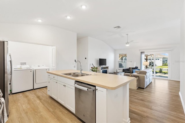 kitchen with sink, independent washer and dryer, stainless steel dishwasher, white cabinets, and a kitchen island with sink