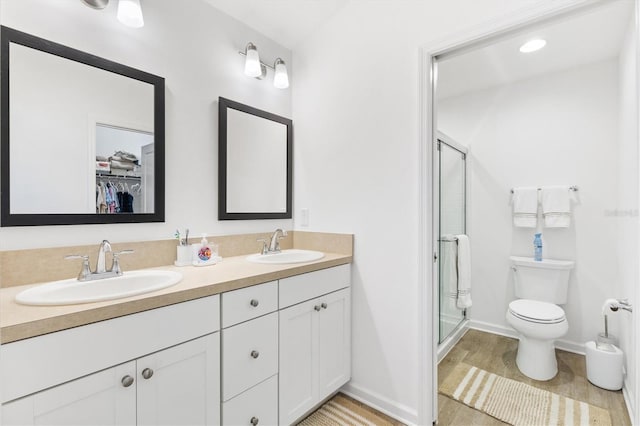 bathroom with toilet, hardwood / wood-style floors, a shower with shower door, and vanity