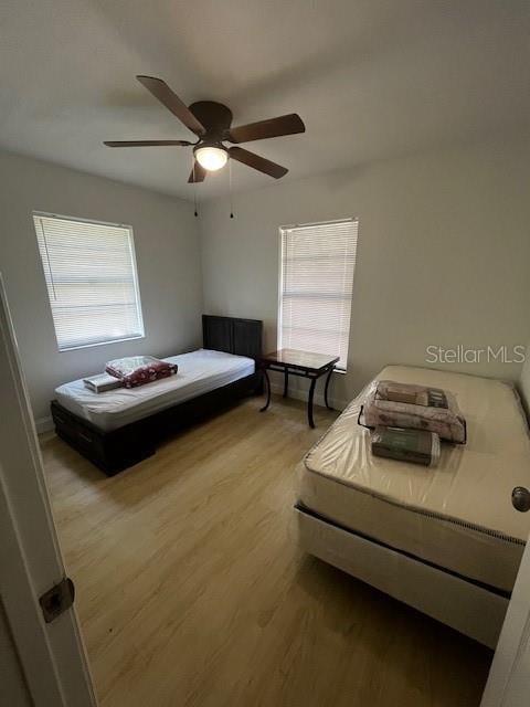 bedroom featuring ceiling fan, multiple windows, and light hardwood / wood-style flooring