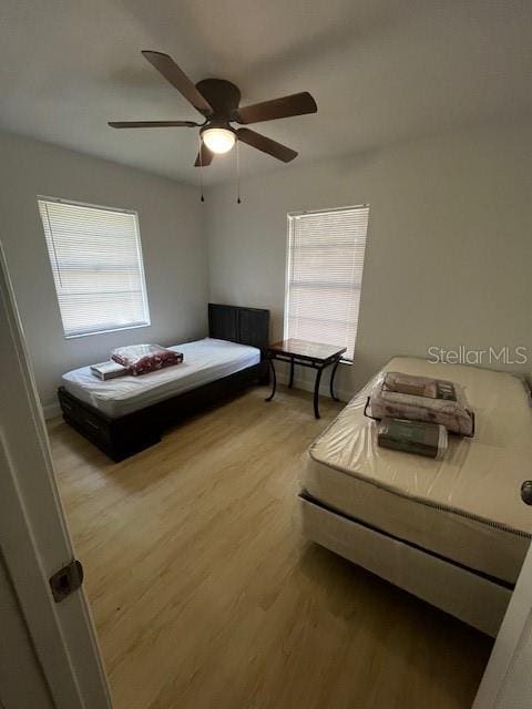 unfurnished bedroom with ceiling fan, hardwood / wood-style flooring, and multiple windows