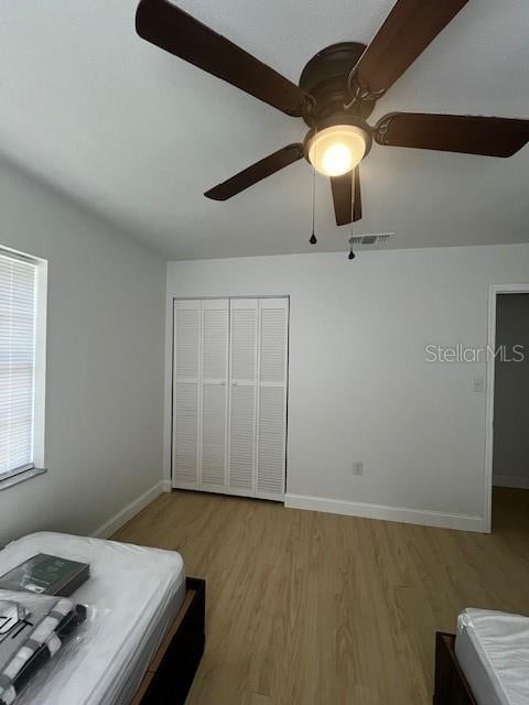 bedroom featuring light hardwood / wood-style flooring, a closet, and ceiling fan