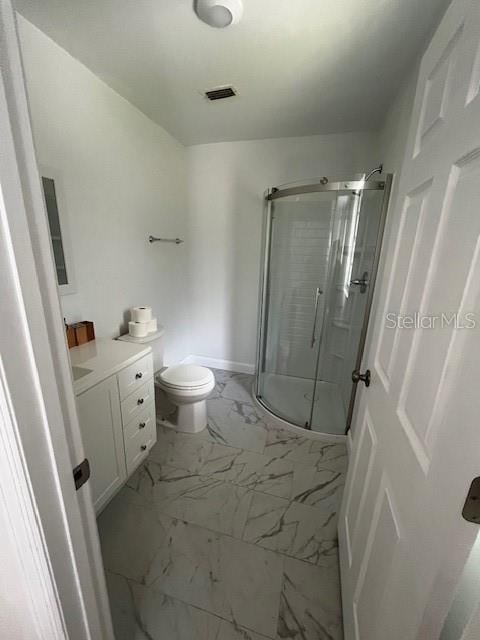 bathroom featuring vanity, an enclosed shower, and toilet