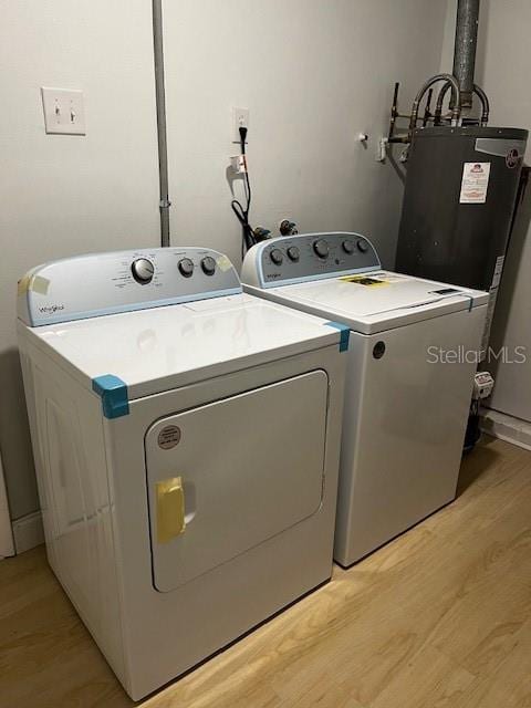 washroom featuring water heater, washing machine and dryer, and light wood-type flooring