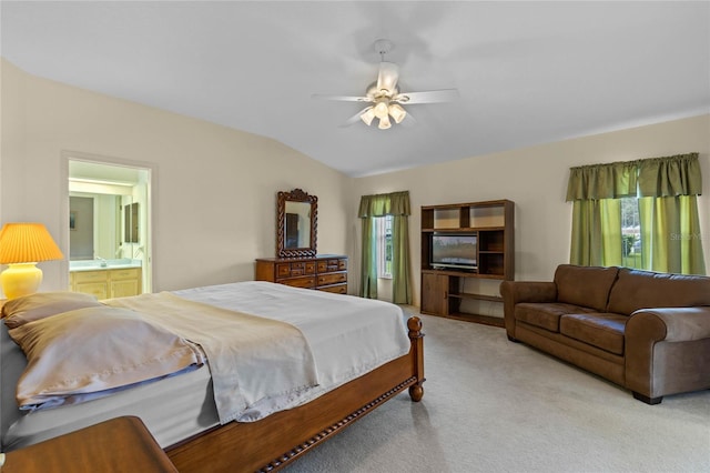 bedroom featuring multiple windows, ceiling fan, ensuite bathroom, and vaulted ceiling