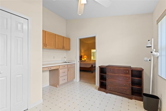 kitchen with lofted ceiling, built in desk, sink, and ceiling fan