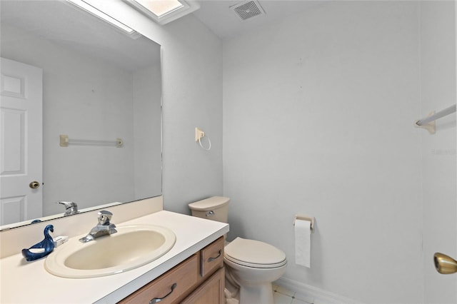 bathroom featuring vanity, toilet, tile patterned floors, and a skylight