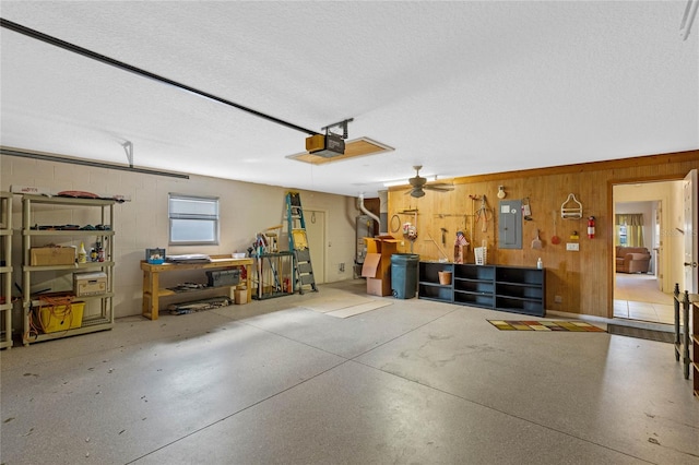 garage featuring a garage door opener, wood walls, electric panel, and ceiling fan