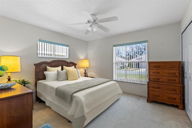 bedroom with light carpet, multiple windows, a closet, and ceiling fan