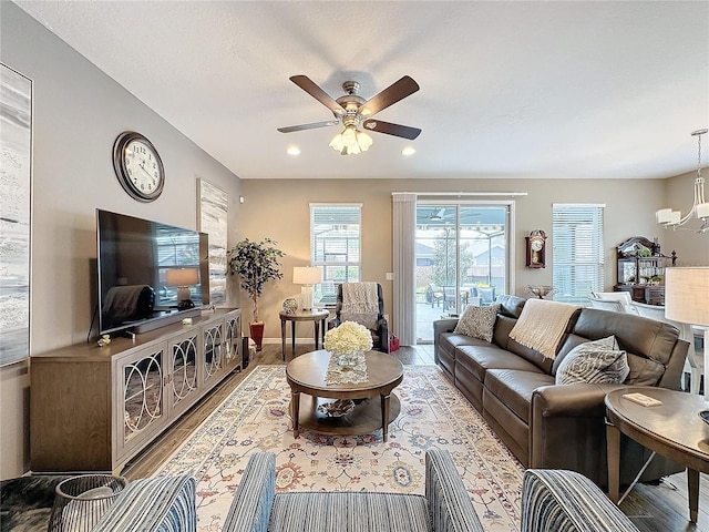 living room with ceiling fan with notable chandelier and hardwood / wood-style floors