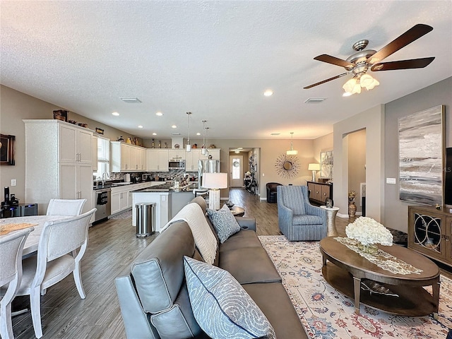 living room featuring hardwood / wood-style floors, a textured ceiling, and ceiling fan