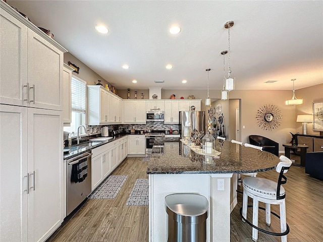 kitchen featuring sink, a center island, white cabinets, appliances with stainless steel finishes, and light hardwood / wood-style floors