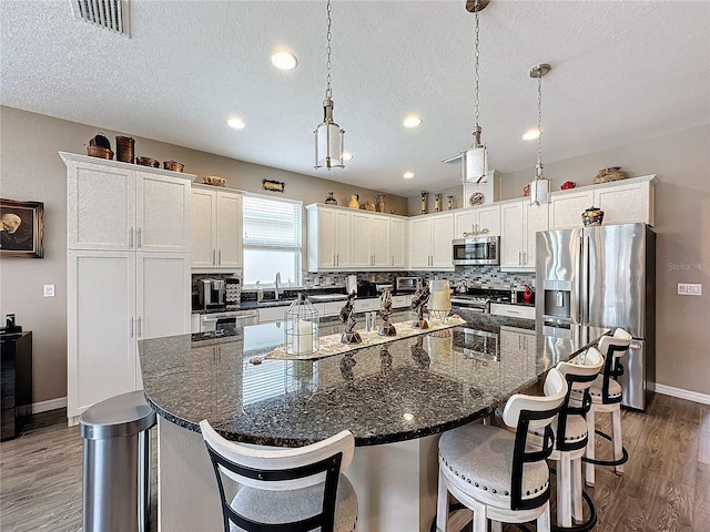 kitchen with appliances with stainless steel finishes, a textured ceiling, and a large island