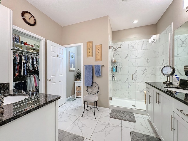 bathroom featuring a shower with door, a textured ceiling, and vanity