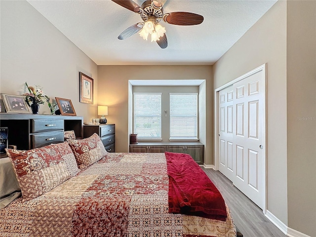 bedroom with light hardwood / wood-style flooring, a textured ceiling, a closet, and ceiling fan