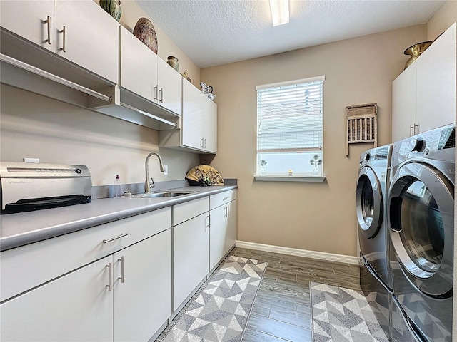 washroom featuring light hardwood / wood-style floors, a textured ceiling, sink, and washer and clothes dryer