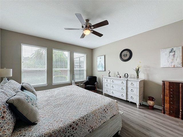 bedroom with ceiling fan, a textured ceiling, and dark hardwood / wood-style flooring