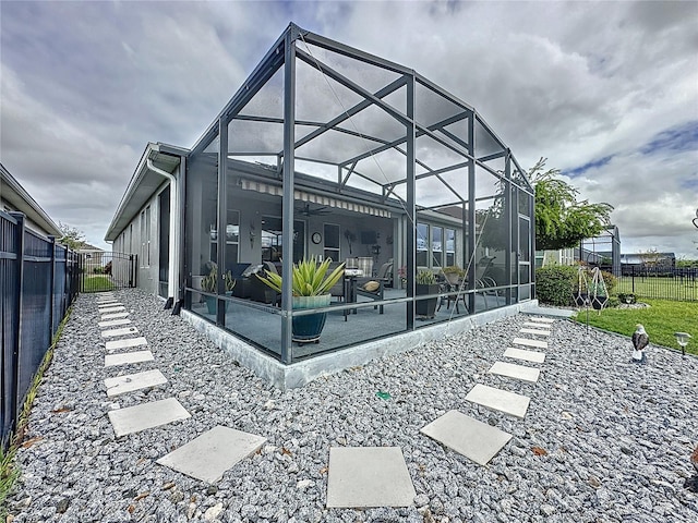 rear view of house featuring glass enclosure, ceiling fan, and a patio area