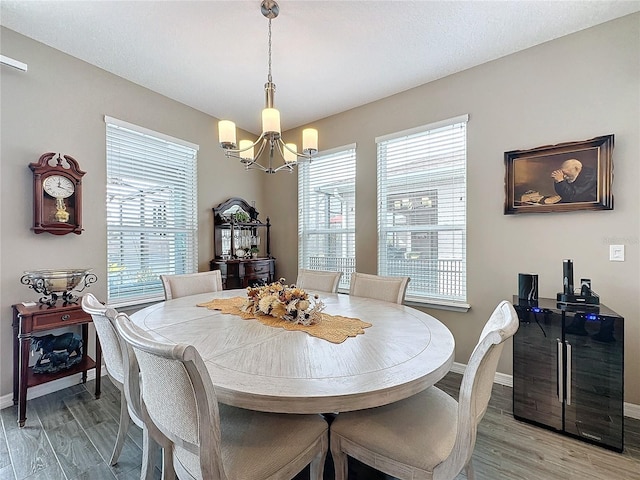 dining area with light wood-type flooring and an inviting chandelier