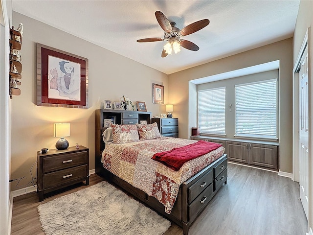 bedroom with ceiling fan, wood-type flooring, and a textured ceiling