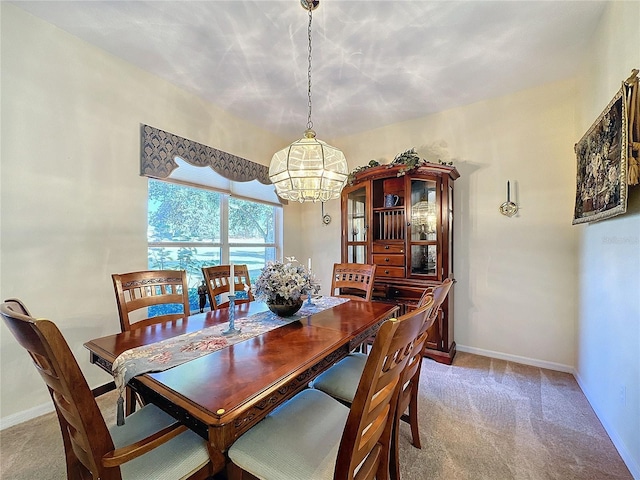 carpeted dining area with a chandelier