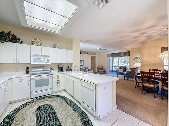 kitchen with sink, kitchen peninsula, light colored carpet, white appliances, and white cabinets