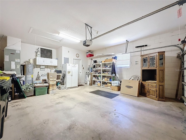 garage with water heater, white fridge with ice dispenser, a garage door opener, and heating unit