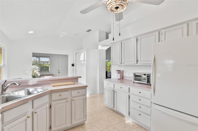 kitchen featuring lofted ceiling, white cabinets, light tile patterned floors, white fridge, and sink