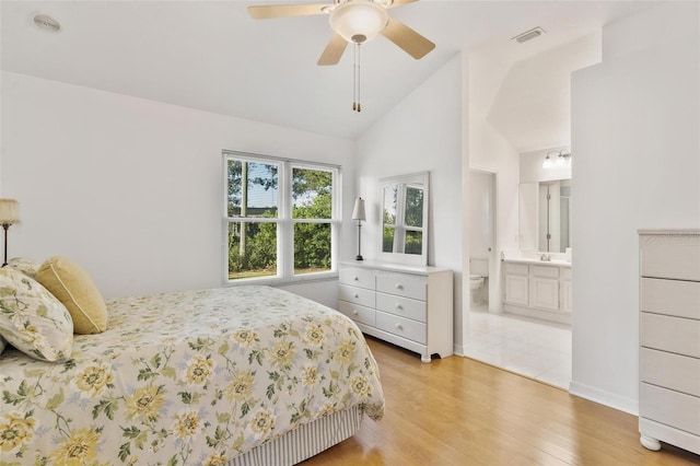 bedroom featuring light hardwood / wood-style floors, high vaulted ceiling, ensuite bathroom, and ceiling fan