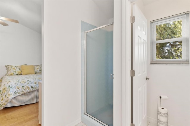 bathroom with a shower with door, vaulted ceiling, and ceiling fan